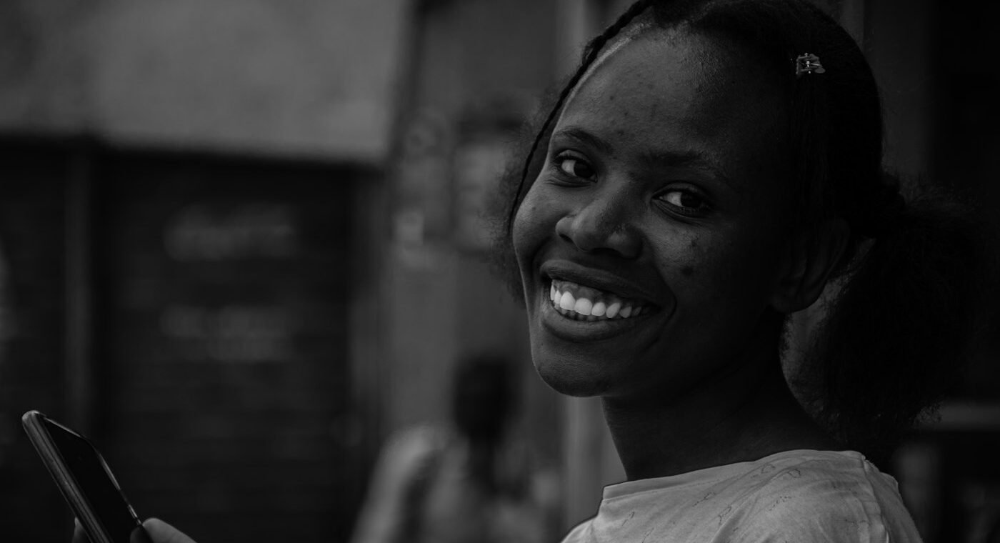 Une femme souriante tenant un téléphone portable